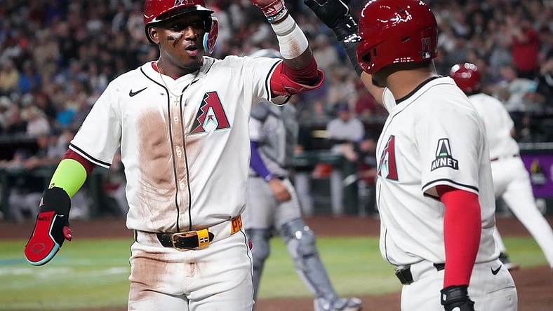 Arizona Diamondbacks Geraldo Perdomo (2) high-fives teammate Gabriel Moreno (14) after scoring a run against the Colorado Rockies on Opening Day at Chase Field.