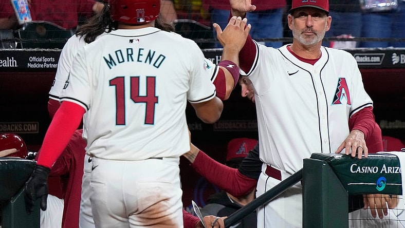 Diamondbacks manager Torey Lovullo high fives Alek Thomas and Gabriel Moreno (14) after the two scored on a Thomas home run against the Rockies during a game at Chase Field.