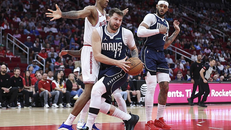 Mar 31, 2024; Houston, Texas, USA; Dallas Mavericks guard Luka Doncic (77) grabs a rebound away from Houston Rockets forward Jabari Smith Jr. (10) during the first quarter at Toyota Center. Mandatory Credit: Troy Taormina-USA TODAY Sports