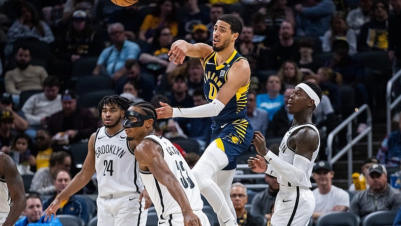 Apr 1, 2024; Indianapolis, Indiana, USA; Indiana Pacers guard Tyrese Haliburton (0) passes the ball while Brooklyn Nets center Nic Claxton (33) defends in the second half at Gainbridge Fieldhouse. Mandatory Credit: Trevor Ruszkowski-USA TODAY Sports