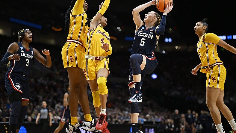 Apr 1, 2024; Portland, OR, USA; UConn Huskies guard Paige Bueckers (5) drives to the basket during the first half against USC Trojans guard Kayla Williams (4) and center Clarice Akunwafo (34)in the finals of the Portland Regional of the NCAA Tournament at the Moda Center. Mandatory Credit: Troy Wayrynen-USA TODAY Sports