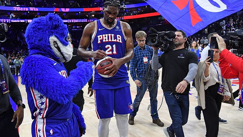 Apr 2, 2024; Philadelphia, Pennsylvania, USA; Philadelphia 76ers center Joel Embiid (21) autographs a basketball as he celebrates win against the Oklahoma City Thunder at Wells Fargo Center. Mandatory Credit: Eric Hartline-USA TODAY Sports
