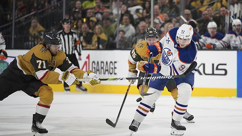 Edmonton Oilers right wing Vasily Podkolzin (92) knocks the puck up the ice against Vegas Golden Knights center William Karlsson (71) during the first period of an NHL hockey game Tuesday, April 1, 2025, in Las Vegas. (AP Photo/John Locher)