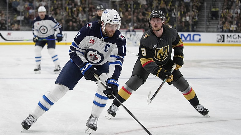 Winnipeg Jets center Adam Lowry (17) skates up the ice against Vegas Golden Knights center Jack Eichel (9) during the first period of an NHL hockey game Thursday, April 3, 2025, in Las Vegas. (AP Photo/John Locher)