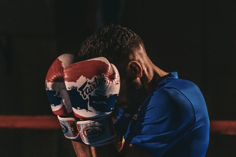 man covering face with boxing gloves