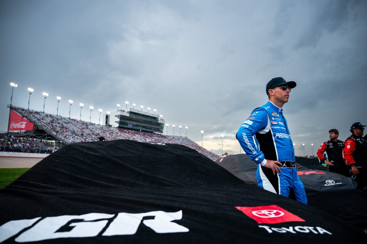 NASCAR Cup Series driver Denny Hamlin waits by his car as rain falls before the Cracker Barrel 400 at Nashville Superspeedway in